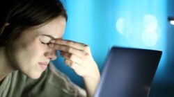 Fatigued woman suffering eyestrain using laptop at night